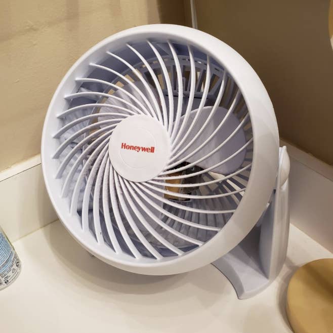 A white circular personal fan on a counter 