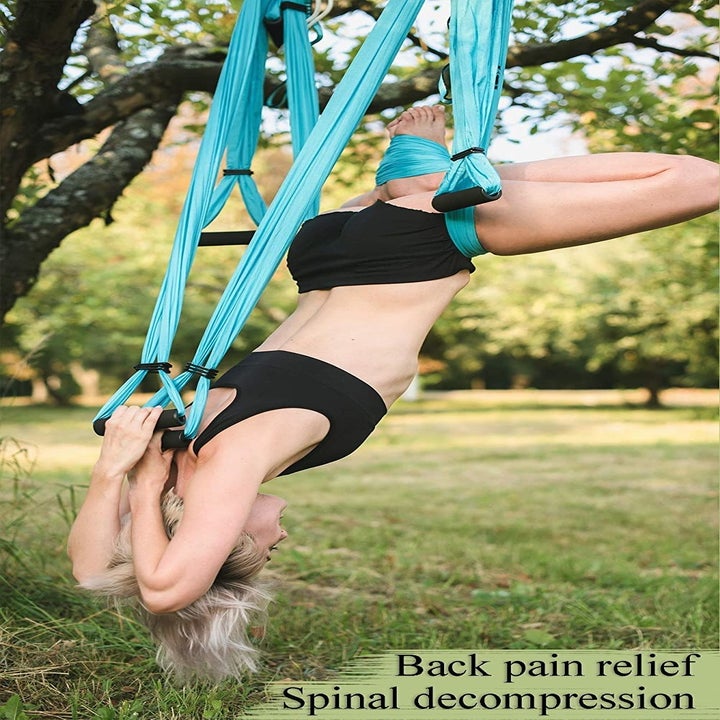 person using the swing to stretch upside down