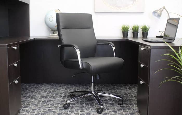 A black desk chair with metal legs and armrests on five caster wheels