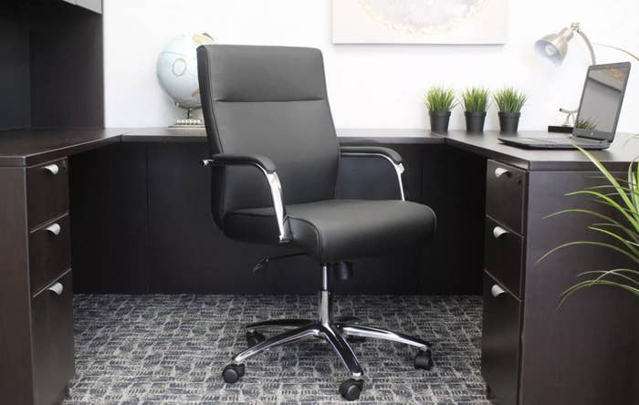 A black desk chair with metal legs and armrests on five caster wheels 