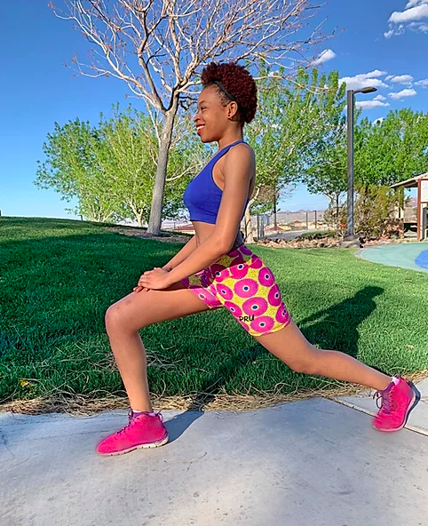 Model wears yellow and pink-printed workout shorts with a blue crop top and pink sneakers