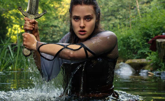 Katherine Langford as Nimue coming out of a lake wielding a sword