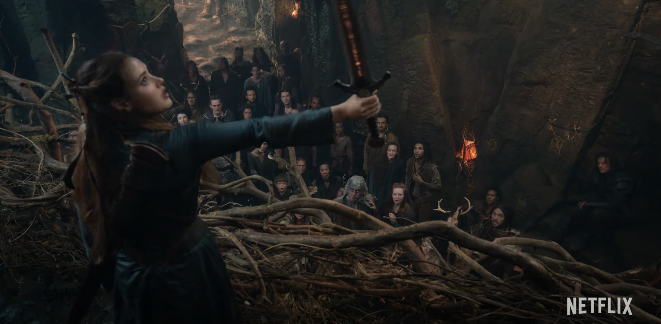 Katherine Langford as Nimue wielding the sword in front of a crowd