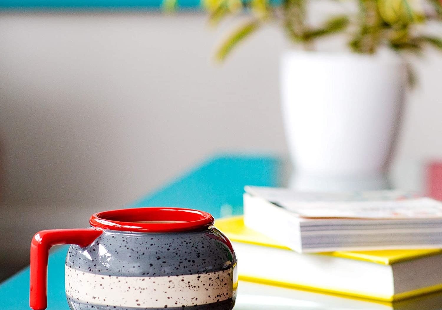 A mug in the shape of a curling rock on a side table