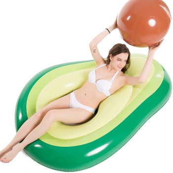 A model laying on the avocado-shaped float holding the pit ball in their hands