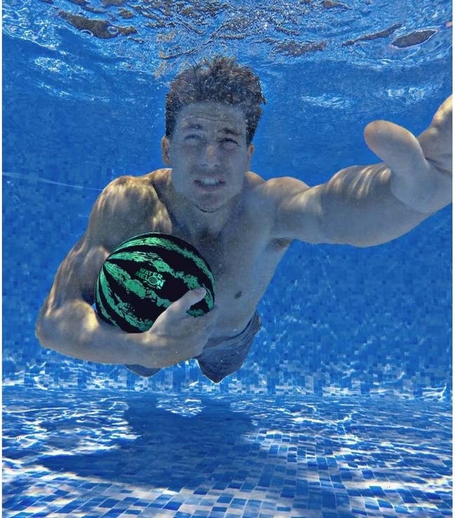 A model swimming underwater with the ball in their arm