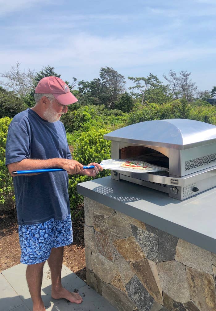 My father putting a pizza into his pizza oven.