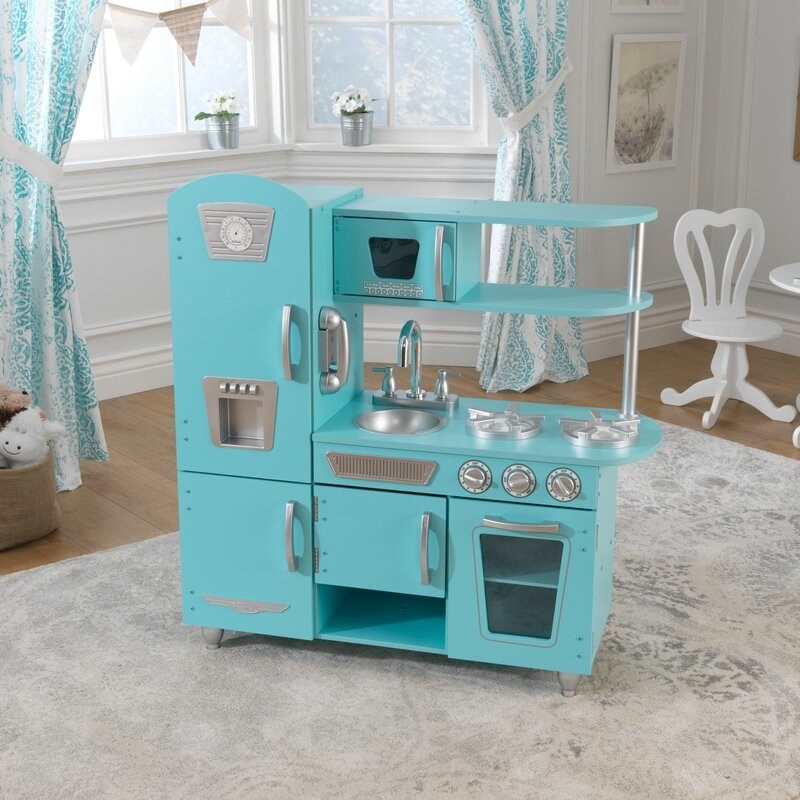 a mini retro-styled kitchen in turquoise blue with a fridge, freezer, stove, oven, sink, microwave, and shelving