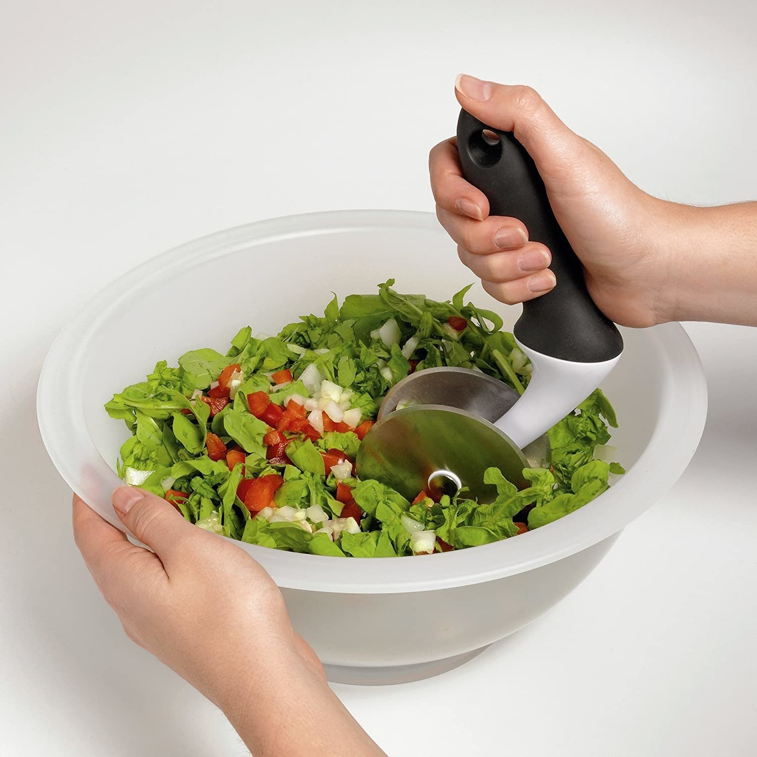 A bowl filled with salad vegetables being chopped with the tool inside.