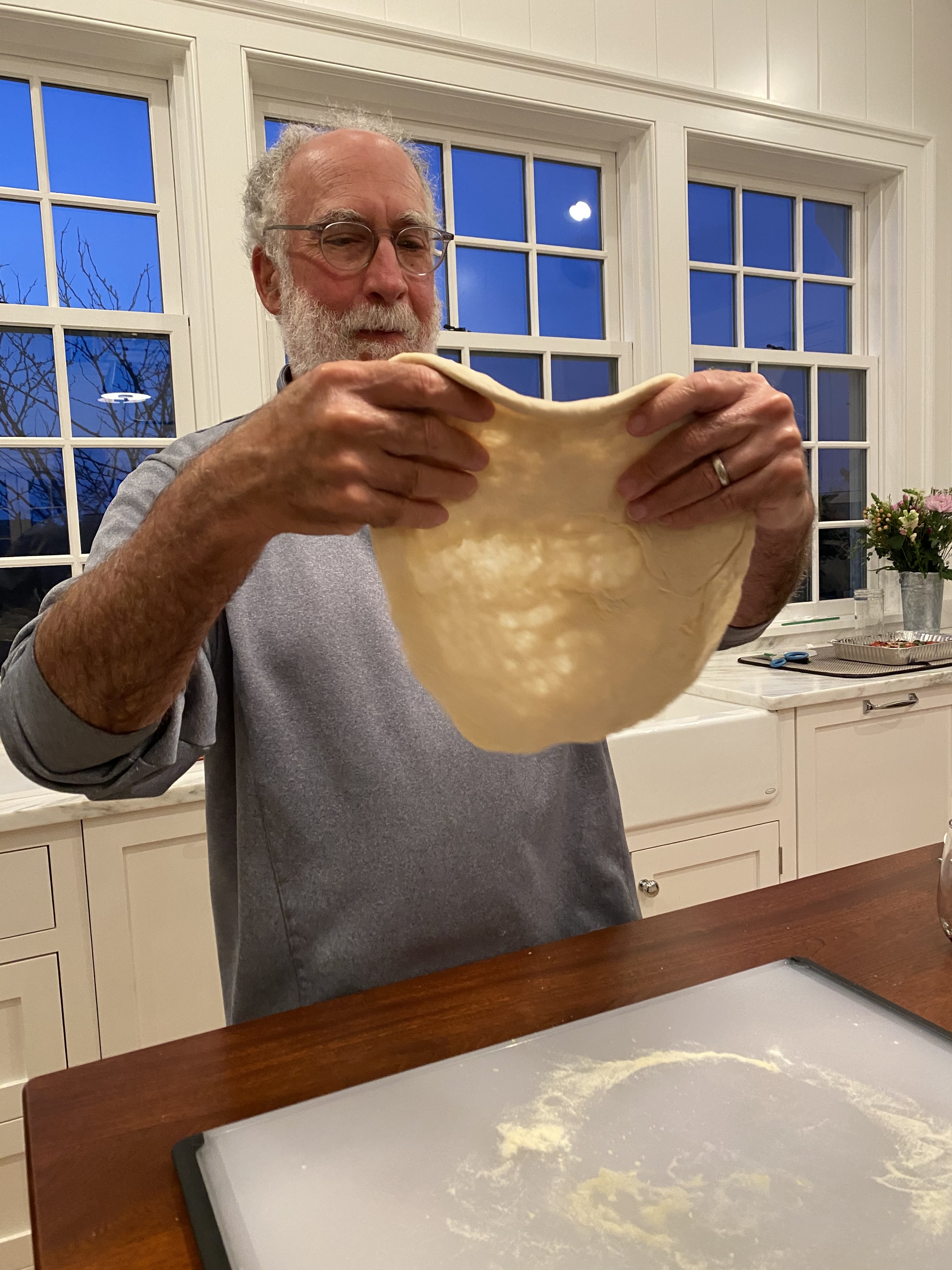 My father expanding dough to make a pizza pie.