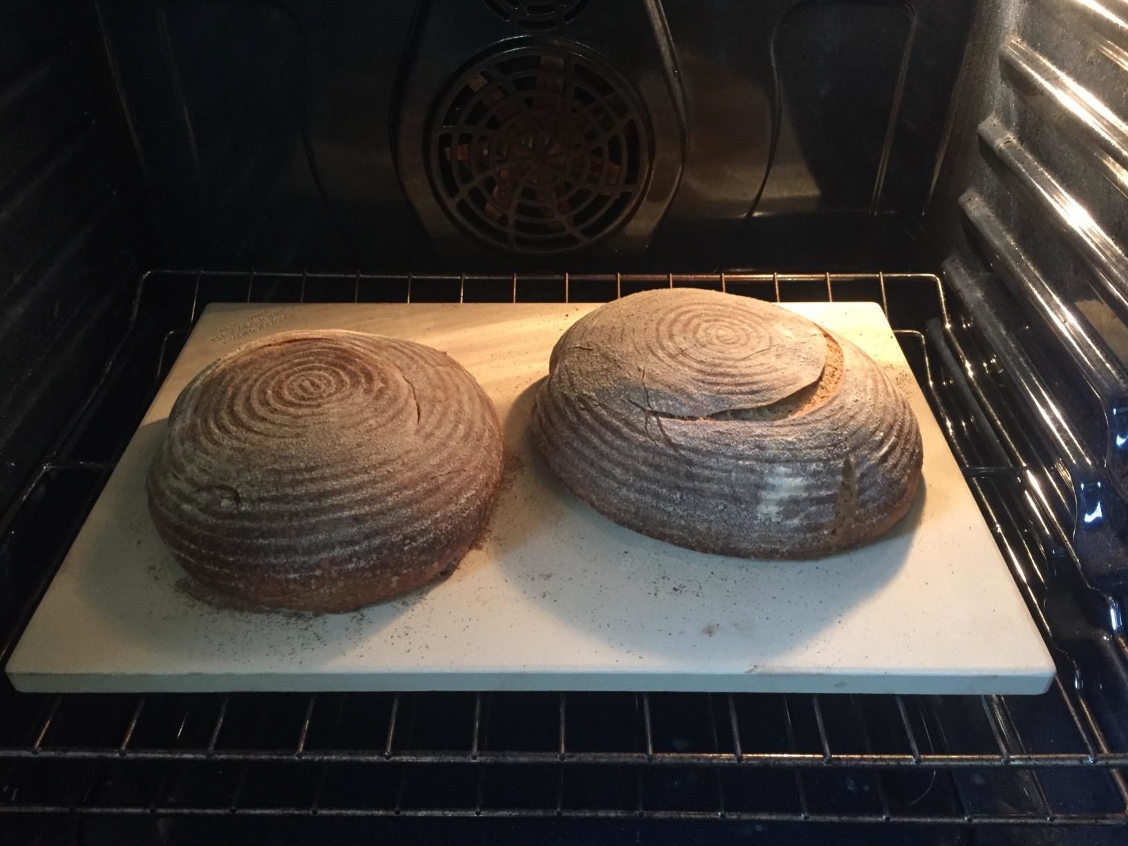 Two loaves of bread cooking on a pizza stone.