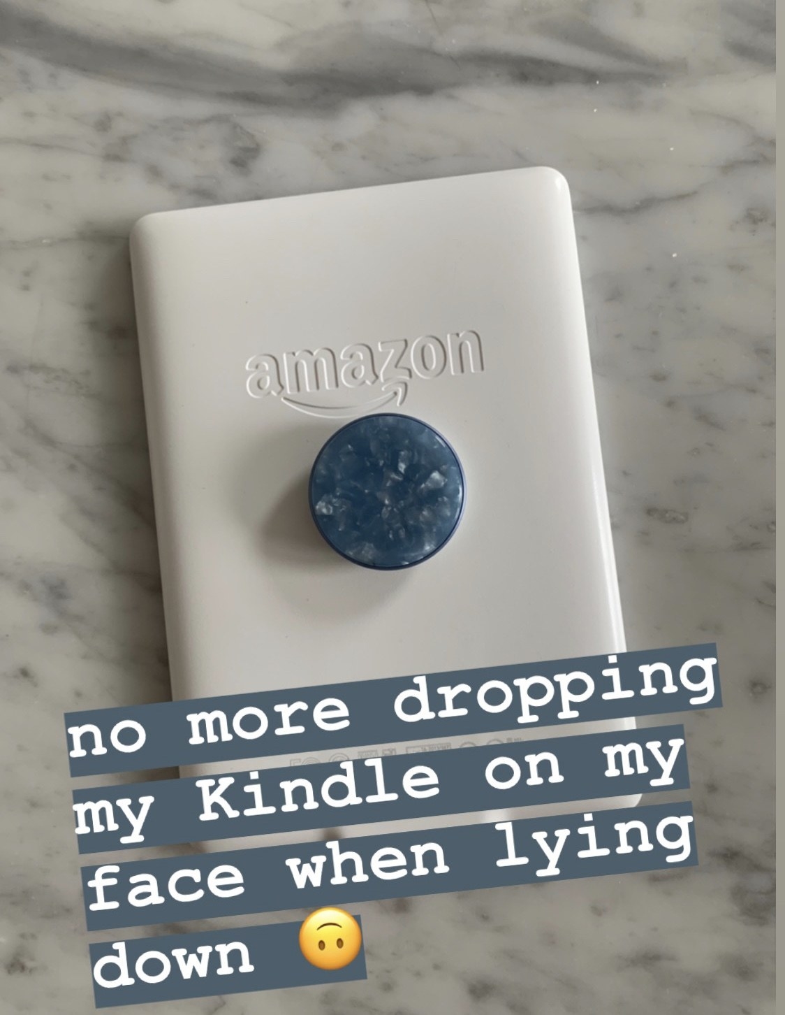 A white kindle with a blue acetate popsocket, with the text &quot;no more dropping my Kindle on my face when lying down&quot;