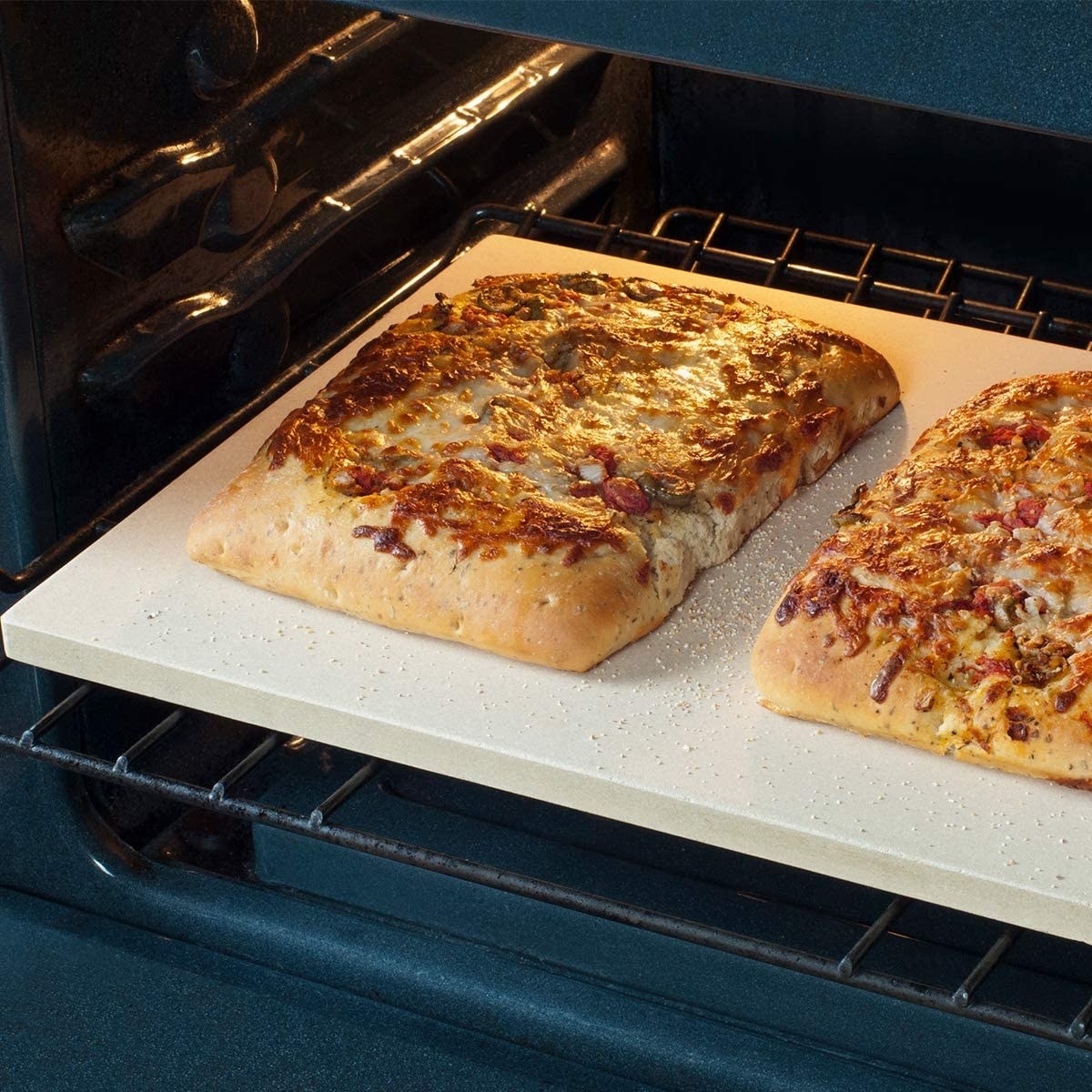 Two rectangular pizzas cooking on a pizza stone. 