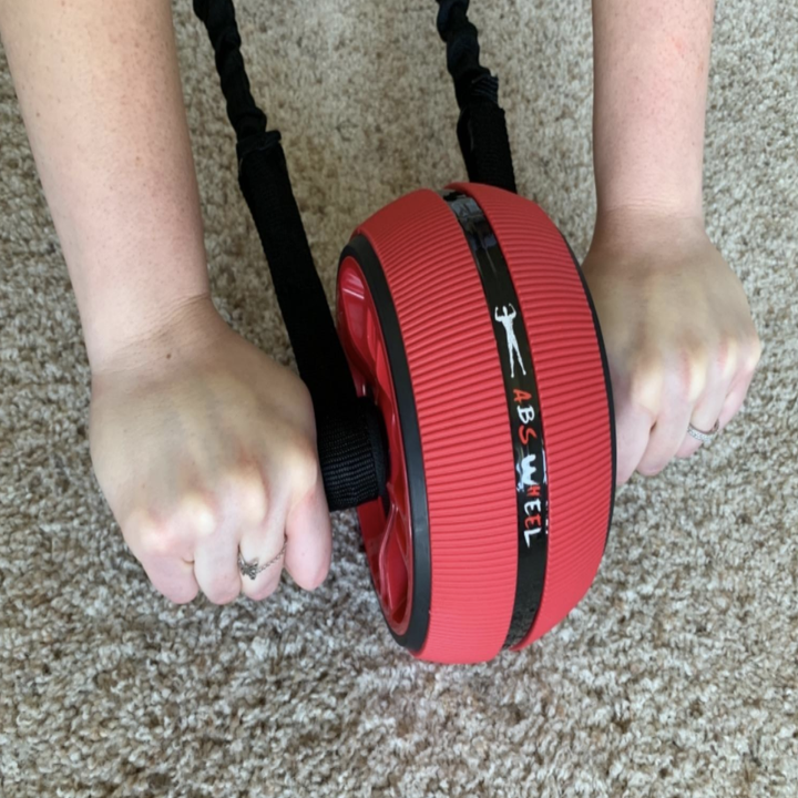 Reviewer pic using the ab roller with their hands on the handles on the floor