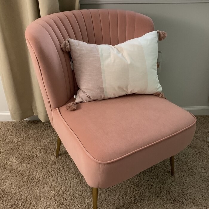 the blush velvet chair with gold, metal legs and a throw pillow on it