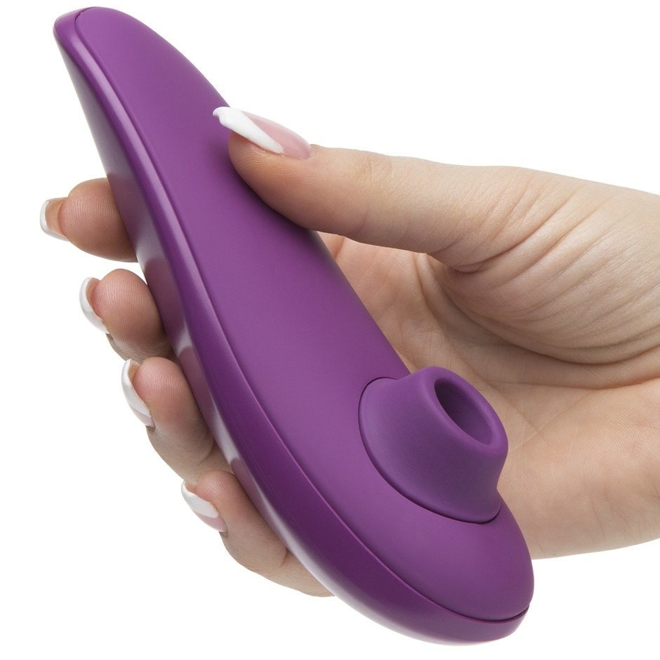 A hand holding the purple toy, which has a very slightly curved handle