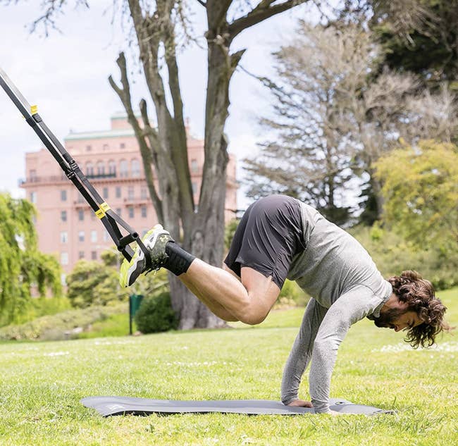 Model uses a TRX Suspension Training System to do a full-body move outside