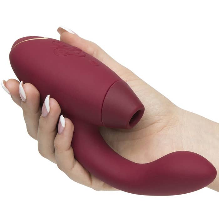 A hand holding the toy, which is shaped almost like a mini hairdryer, but with a handle that curves in with a bulbous end