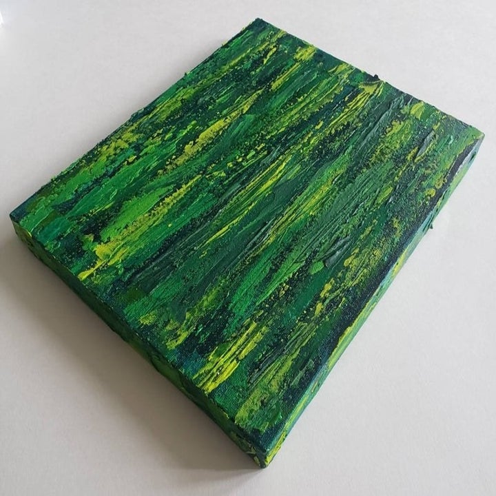canvas painted with layers of green acrylic paint in abstract stroke pattern