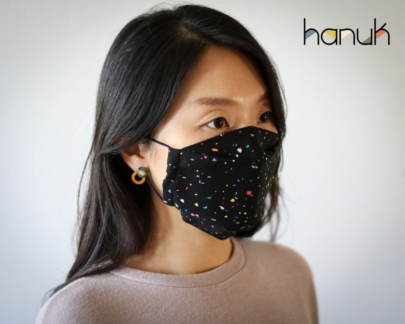 A model in a black rainbow-speckled face mask 