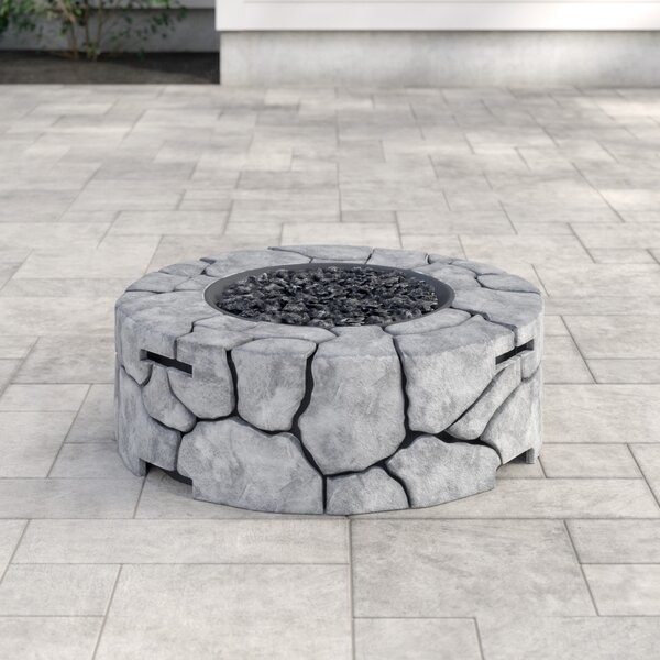 gray stone looking circular low firepit with dark gray gravel in middle that emits the flame