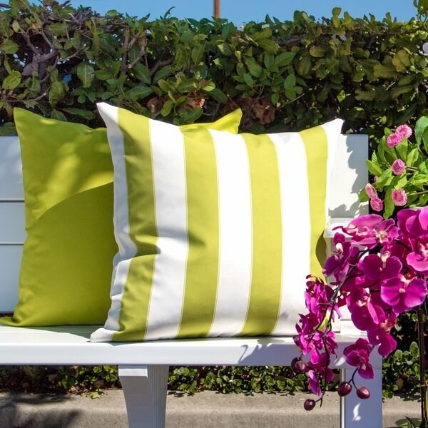 white outdoor bench with two lime green and white square throw pillows