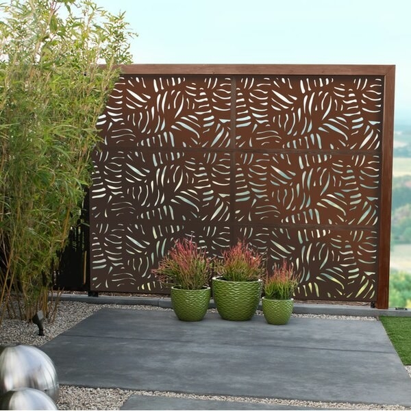 outdoor area with large bronze color fence panel that has a leaf pattern that lets in som light