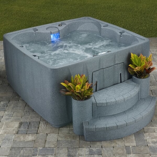 outdoor patio area with gray hot tub with two steps leading up to it and two planters on front