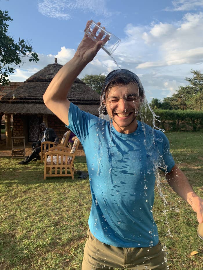 James Leitner stands in a field in Uganda, dumping a glass of clean drinkable water on his head