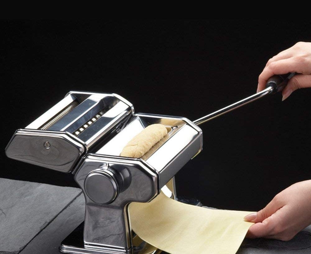 A sheet of pasta being passed through a pasta machine