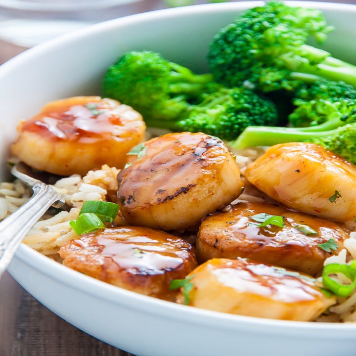 A bowl with seared, glazed scallops and broccoli.