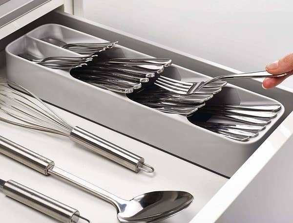 person putting a fork into the gray cutlery organizer 