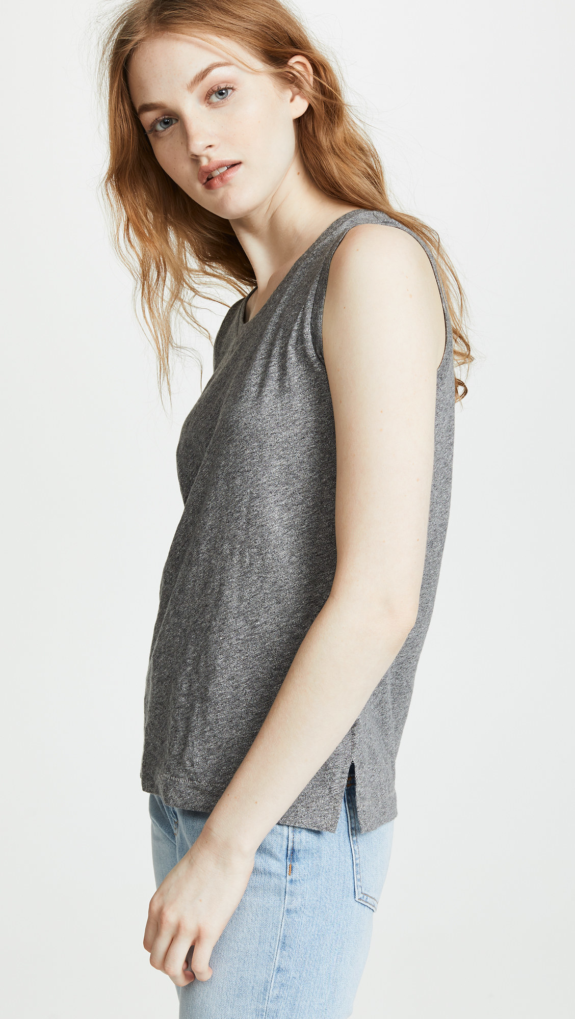a model wearing a grey, heathered muscle tank with tiny slits on the sides