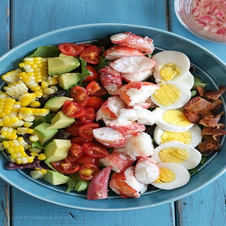Lobster cobb salad in a bowl with corn, bacon, tomato, avocado, and hard boiled egg.