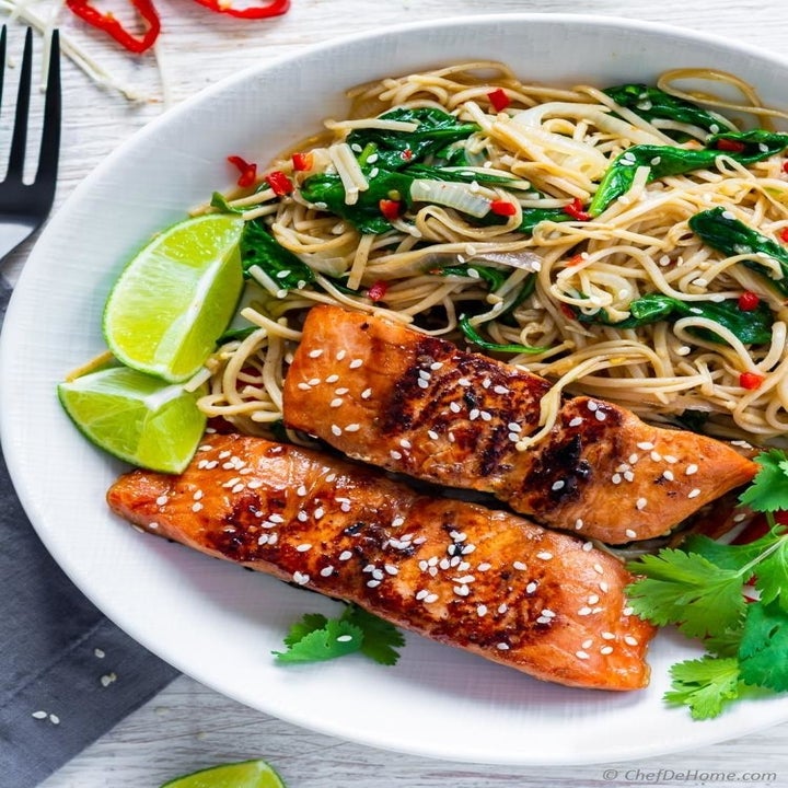 Marinated salmon on top of a bed of soba noodles with spinach.
