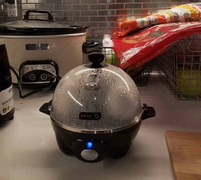The black version of the egg cooker with the transparent lid on which is full of steam