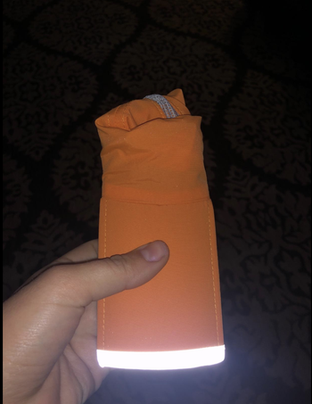 A reviewer holding the hat folded up neatly, showing its reflective quality in the dark 