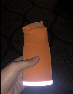 A reviewer holding the hat folded up neatly, showing its reflective quality in the dark 