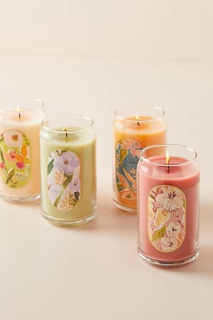 Cuatro velas con cera de diferentes colores y un bonito etiquetado floral.