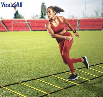 Model uses yellow and black agility ladder in a field
