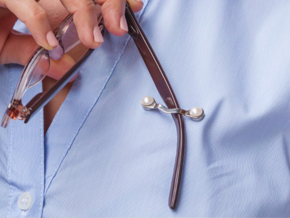 person placing arm of eyeglasses into a metal holder attached to shirt