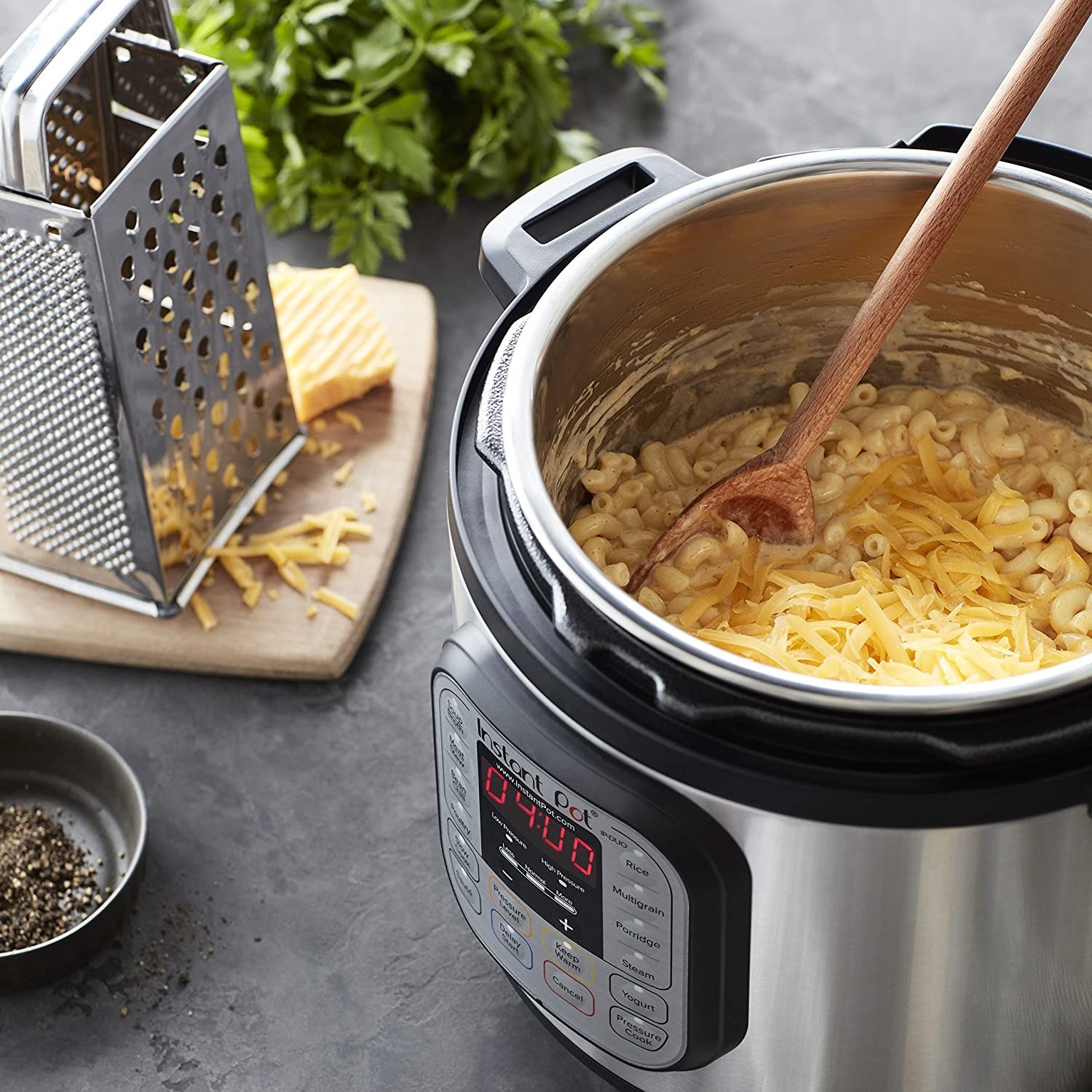 An instant pot with noodles and cheese being stirred