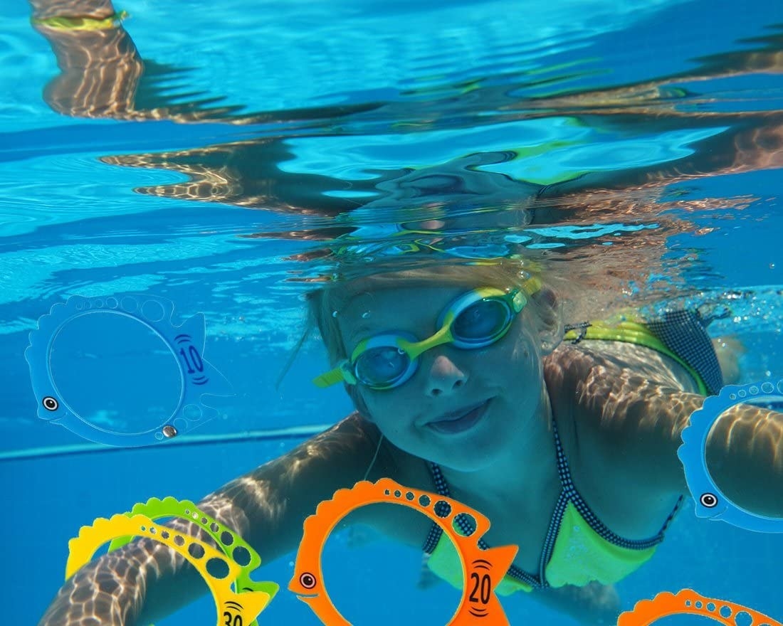 A kid underwater swimming toward the rings