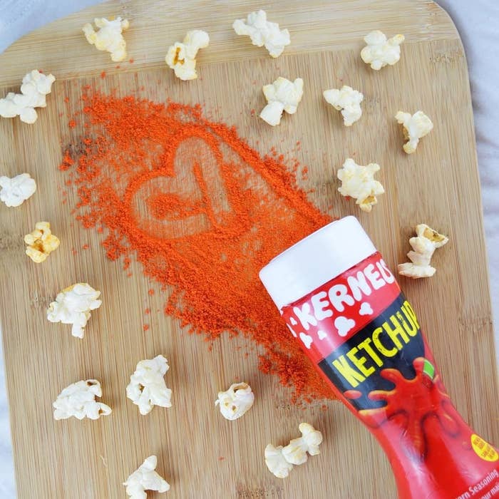 A shaker of ketchup flavouring surrounded by popped kernels of popcorn