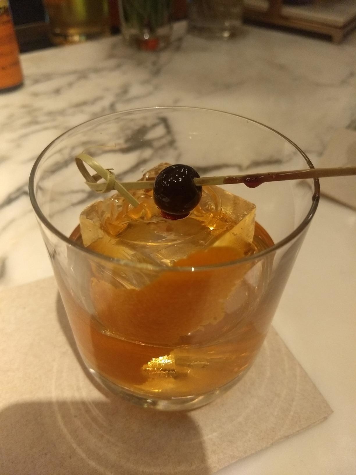 An Old-Fashioned whiskey cocktail with a jumbo ice cube inside of the glass.