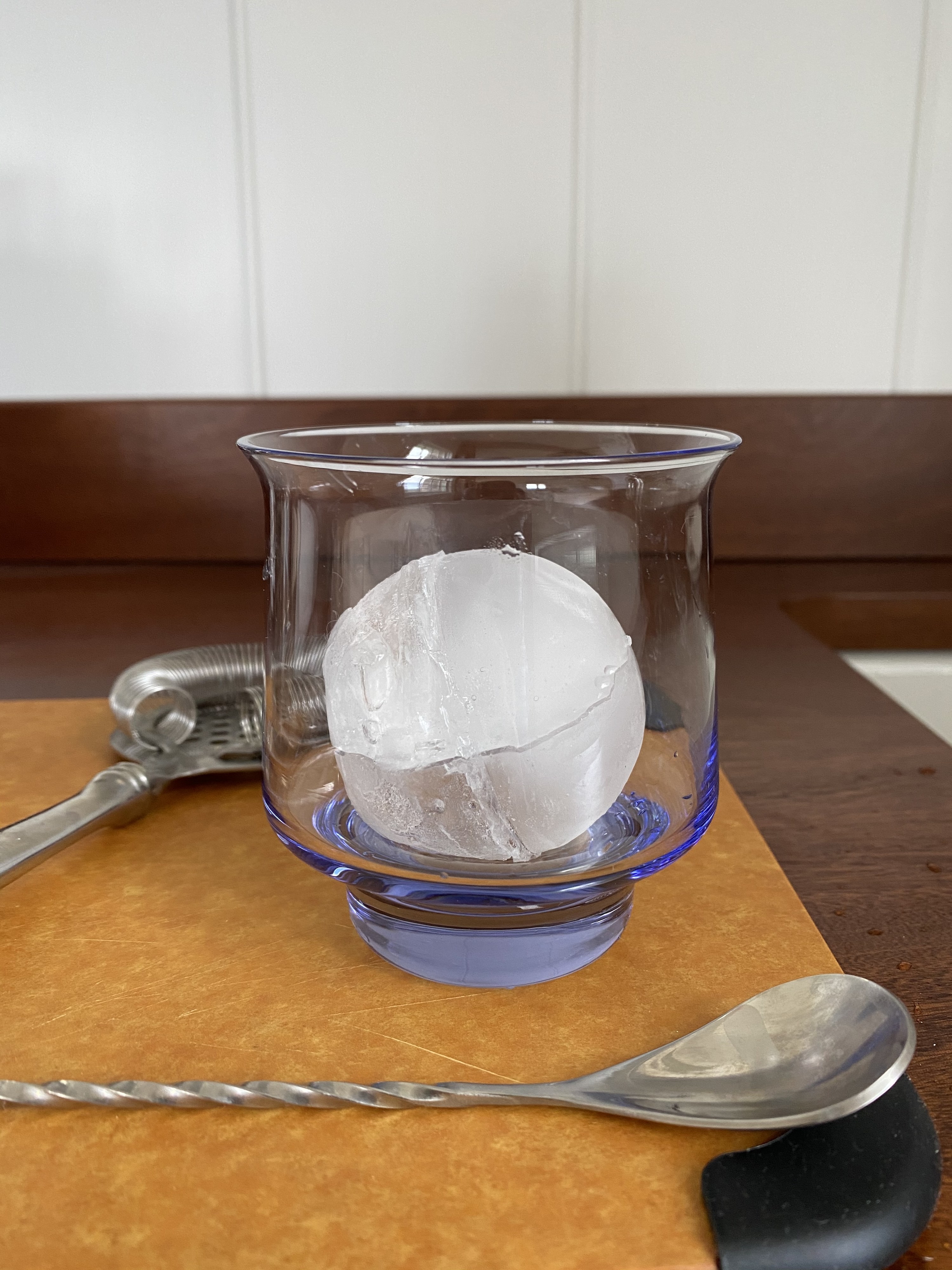 A jumbo spherical ice cube in a cocktail glass.