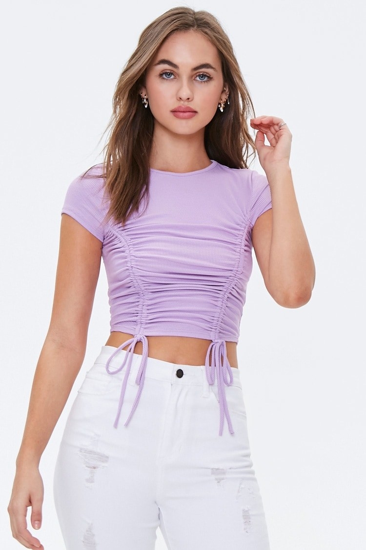 A model wearing the short-sleeved tee in lavender. It has two ties on the bottom that create a ruched effect on the ribbed tee