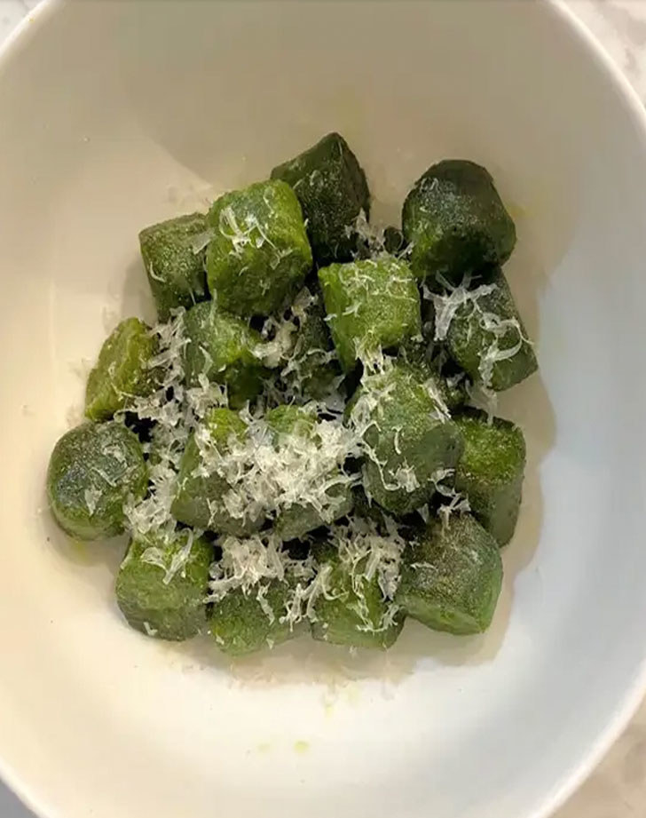 A plate of kale gnocchi with grated Parmesan. 