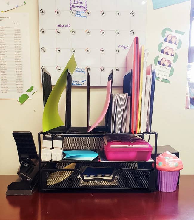 A reviewer's organizer with an assortment of desk supplies inside