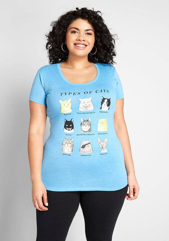 a model wearing the light blue shirt with nine kinds of sassy cats on it with funny descriptions under each one